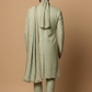 Person wearing a traditional light green sherwani with matching turban on a beige background