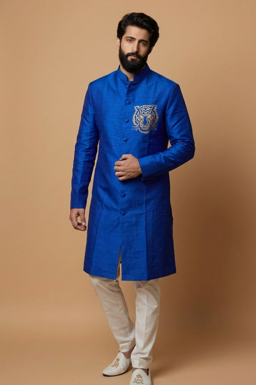 Man wearing a blue traditional coat with a tiger emblem on a beige background