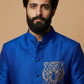 Man wearing a blue embroidered jacket with a tiger design on a beige background