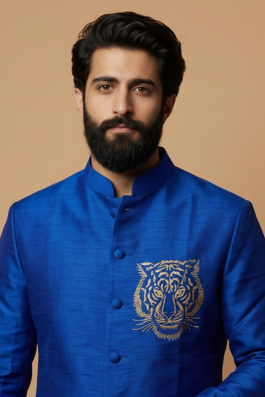 Man wearing a blue embroidered jacket with a tiger design on a beige background