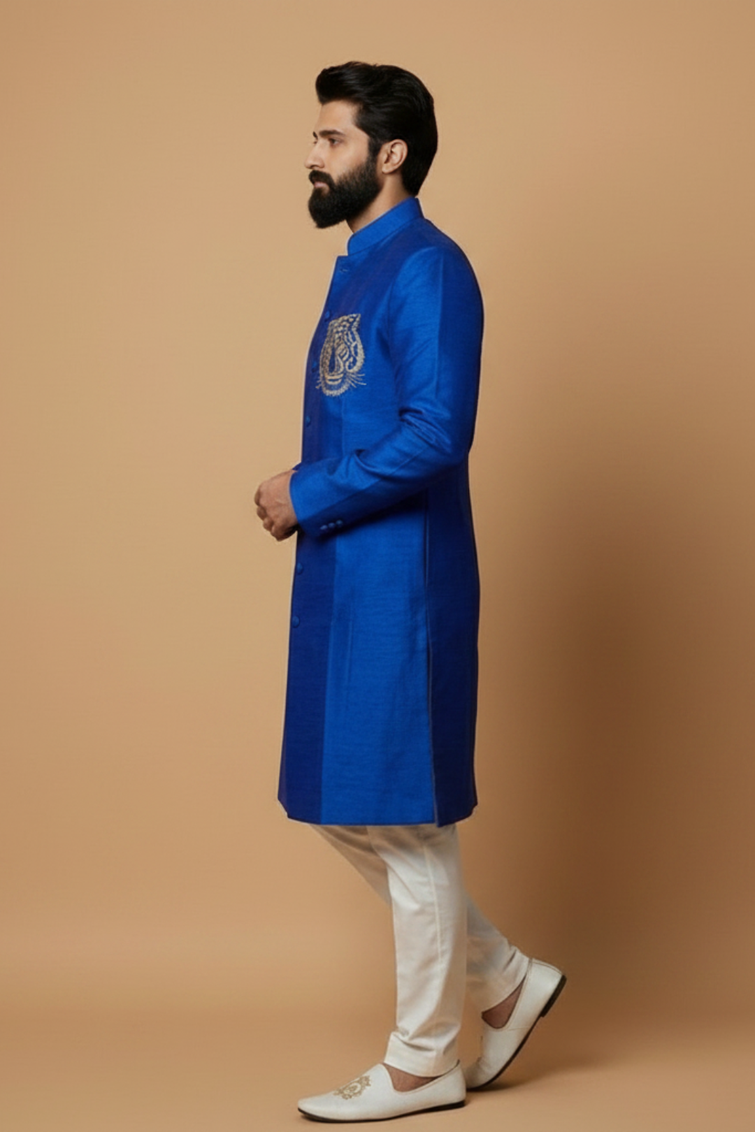 Man wearing a blue kurta with white pants on a beige background
