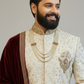 Man wearing a traditional embroidered outfit with a plain background