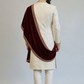 Man wearing a cream sherwani with a maroon shawl on a plain background