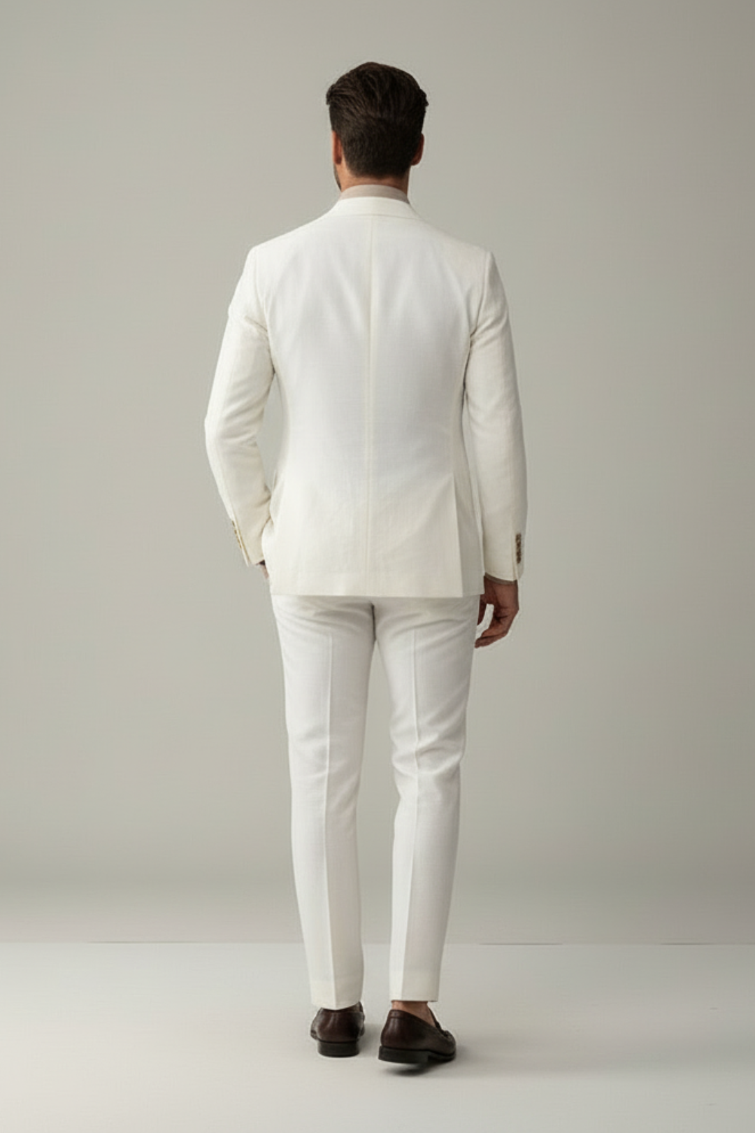 Man wearing a white suit standing against a plain background