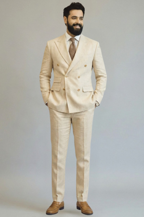 Man wearing a beige suit with a white shirt and brown shoes on a plain background