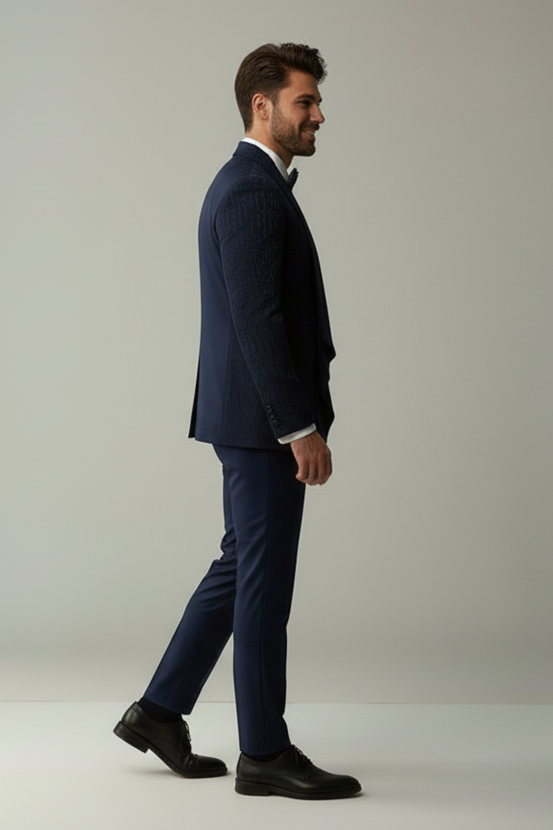 Man wearing a navy suit standing against a plain background