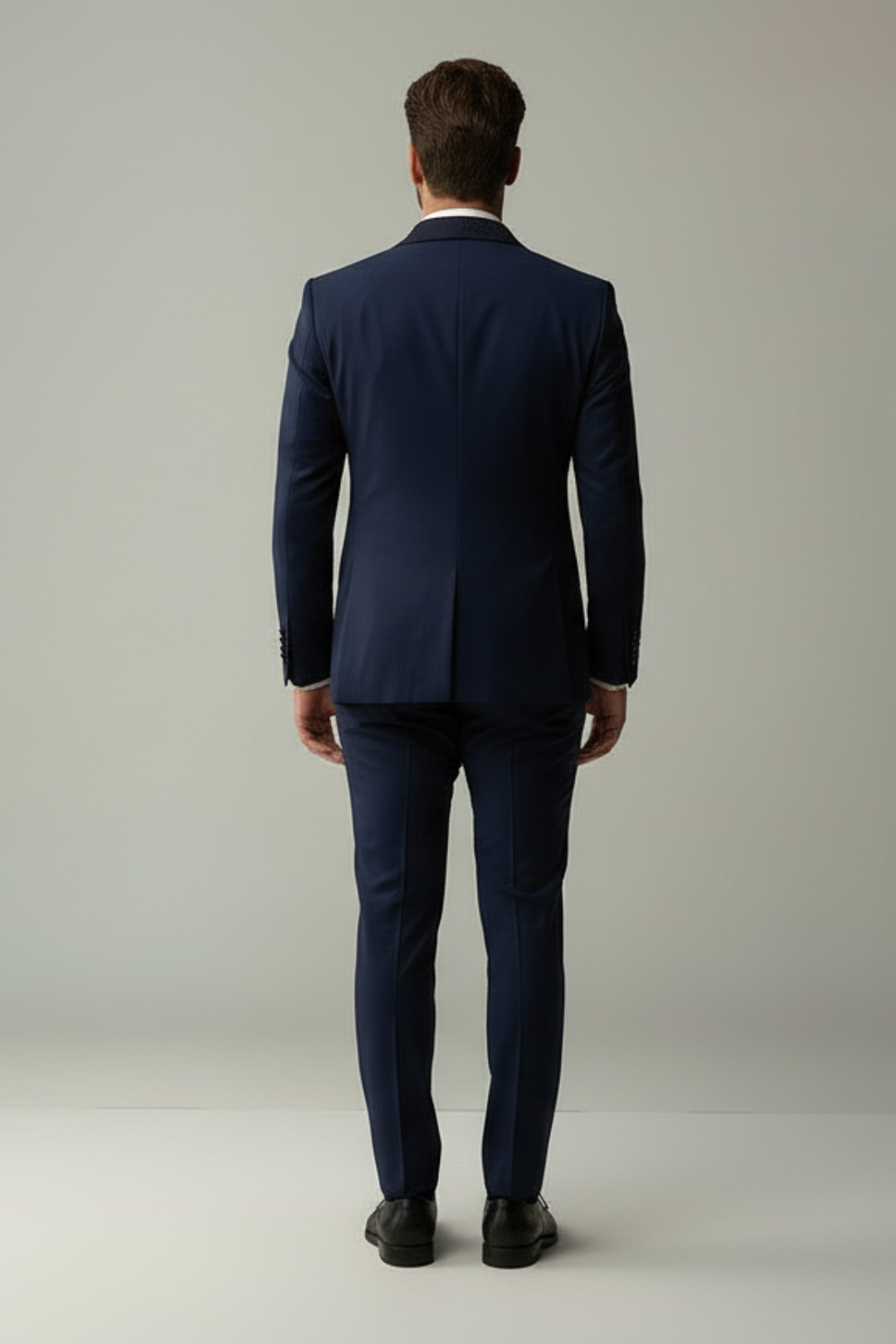 Man wearing a navy suit standing against a plain background