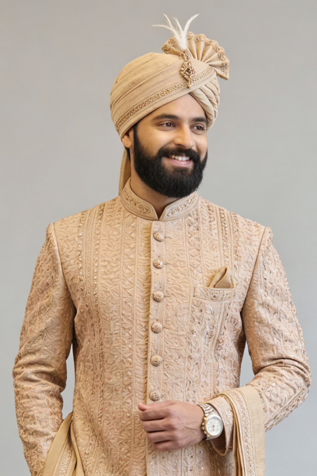 Man wearing a traditional beige sherwani with a turban on a gray background