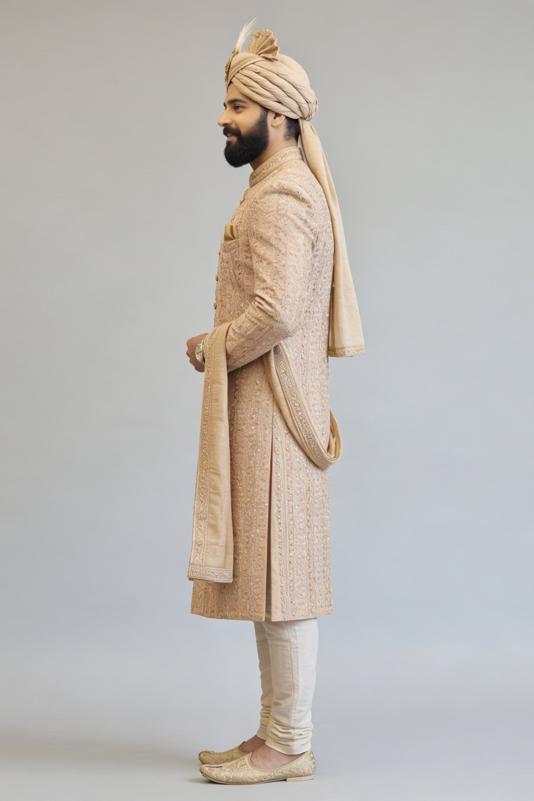 Man wearing a traditional beige sherwani with a turban on a light gray background
