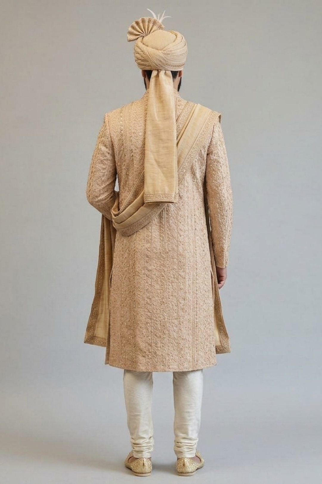 Man wearing a traditional beige kurta with a matching turban and scarf against a plain background