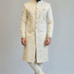 Man wearing a traditional cream sherwani against a plain background