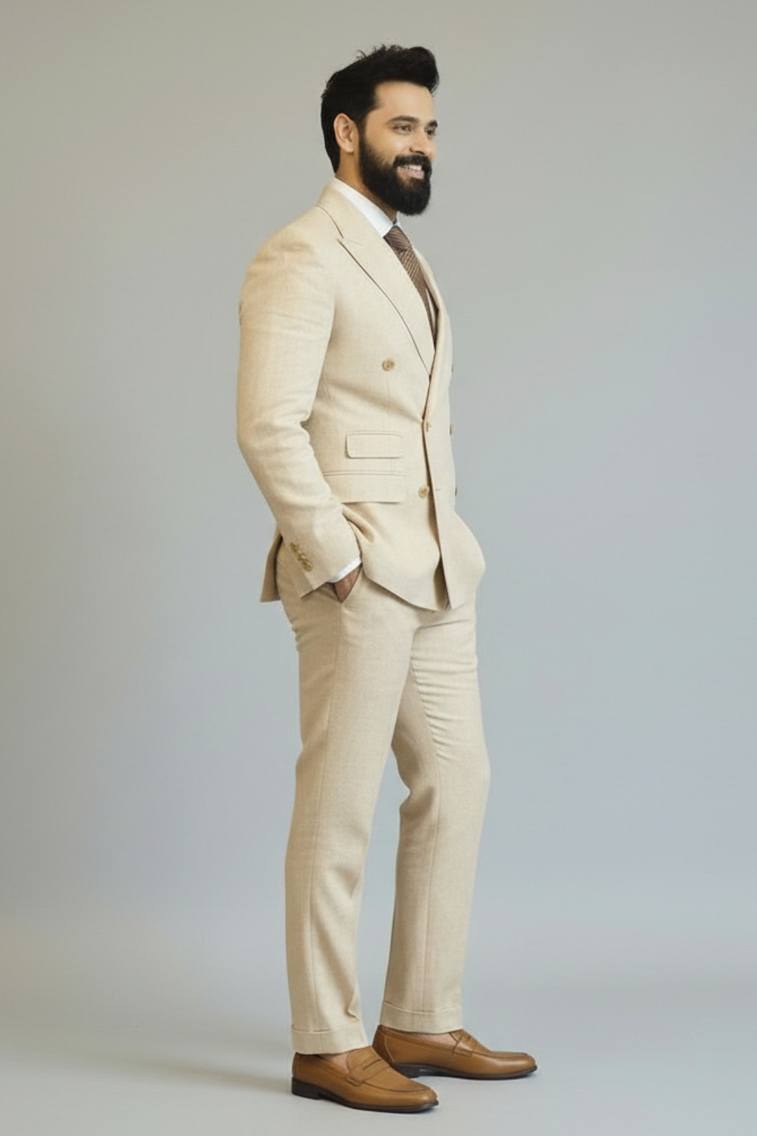 Man wearing a beige suit with a white shirt and brown shoes on a plain background