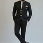 Man wearing a black suit with gold buttons against a plain background