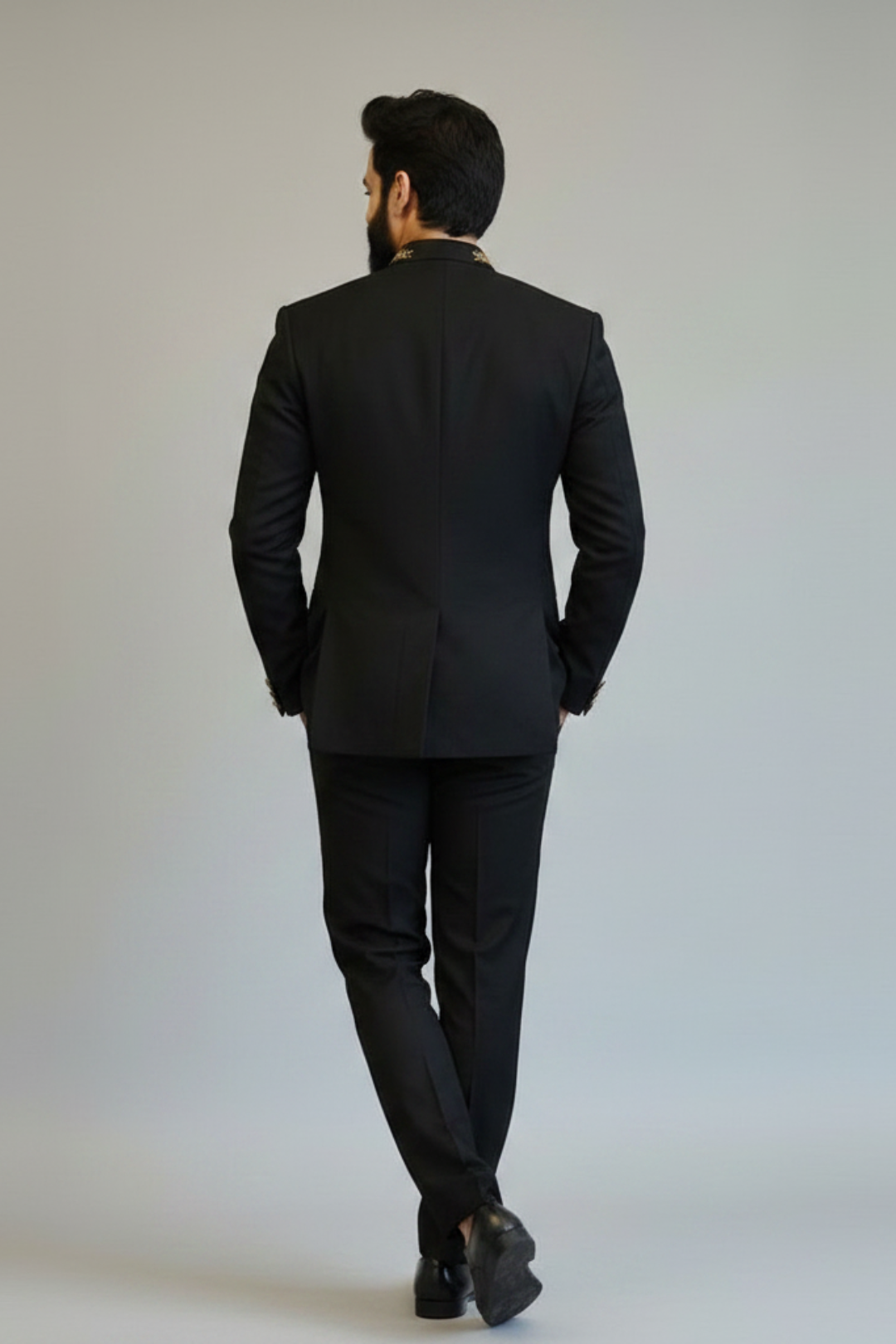Man wearing a black suit against a plain background