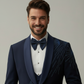 Man wearing a navy blue tuxedo with a bow tie against a plain background