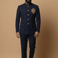 Man wearing a navy blue embroidered suit against a beige background