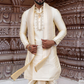 Man in traditional cream sherwani with intricate background