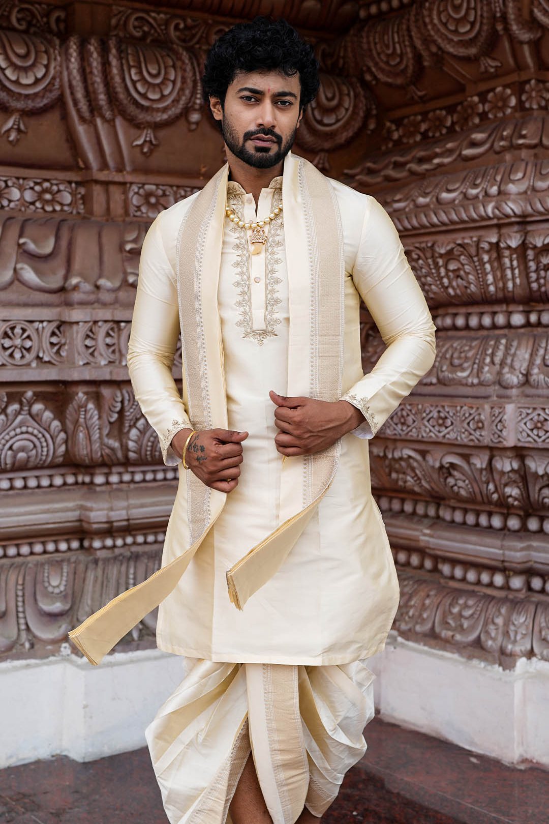 Man in traditional cream sherwani with intricate background