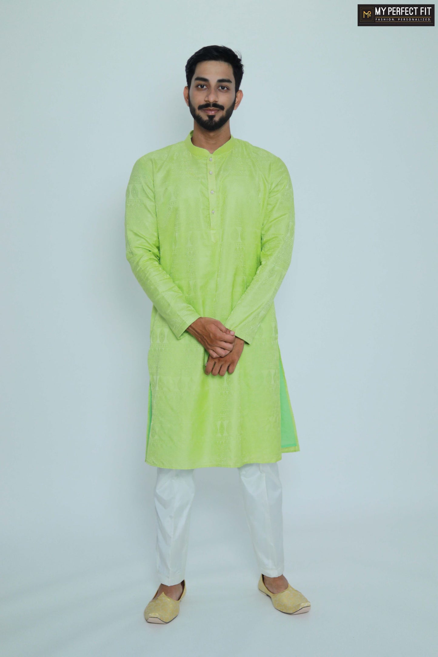 Man wearing a bright green kurta with white pants on a light gray background