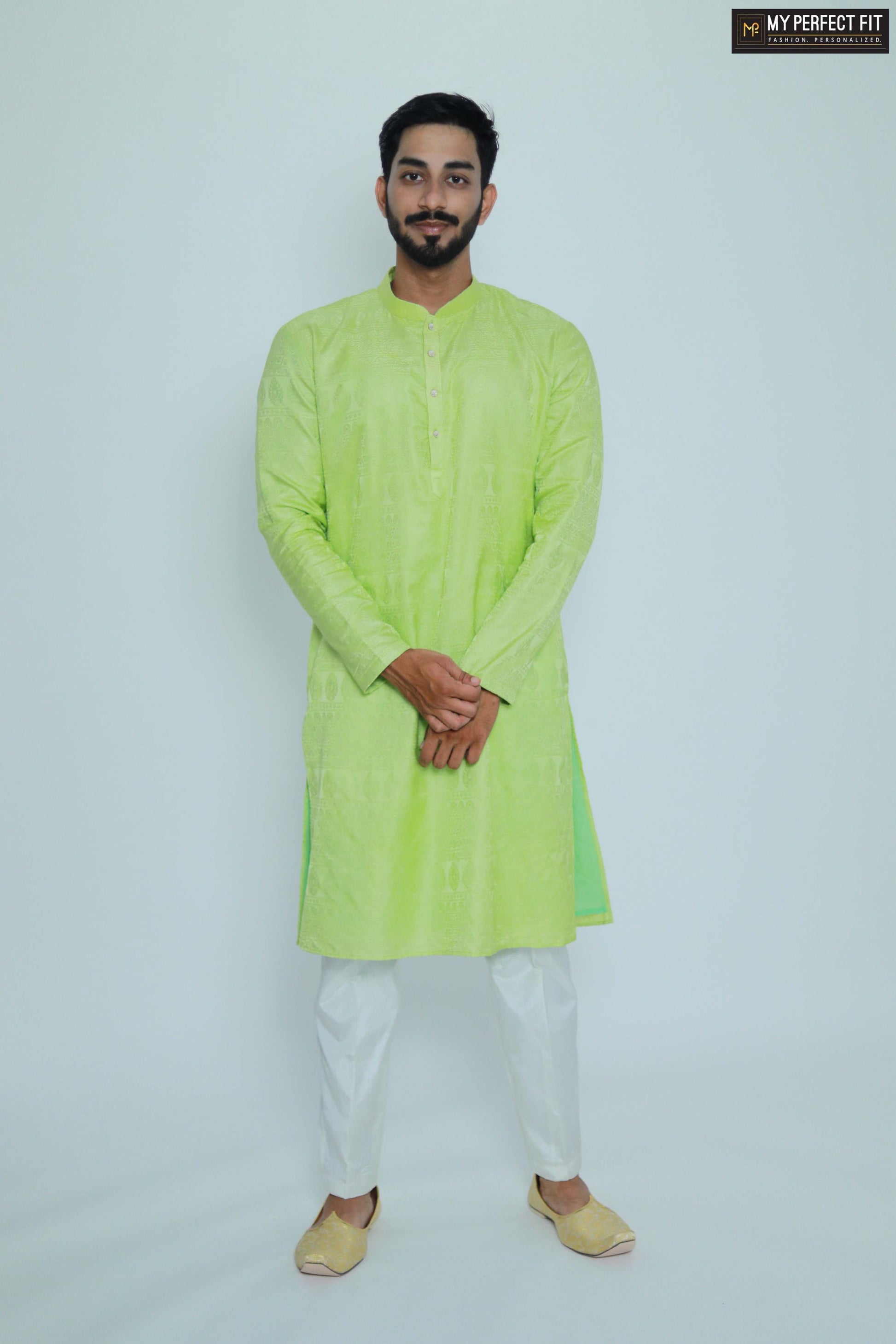 Man wearing a bright green kurta with white pants on a light gray background