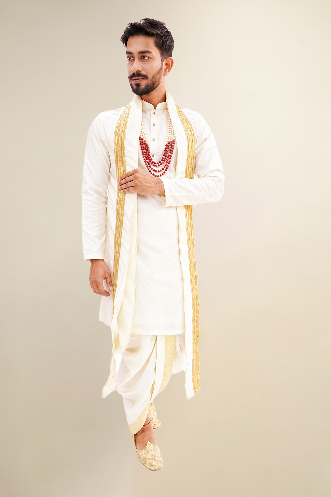 A man wearing a white plain pure pattu kurta set with golden borders and a red necklace.