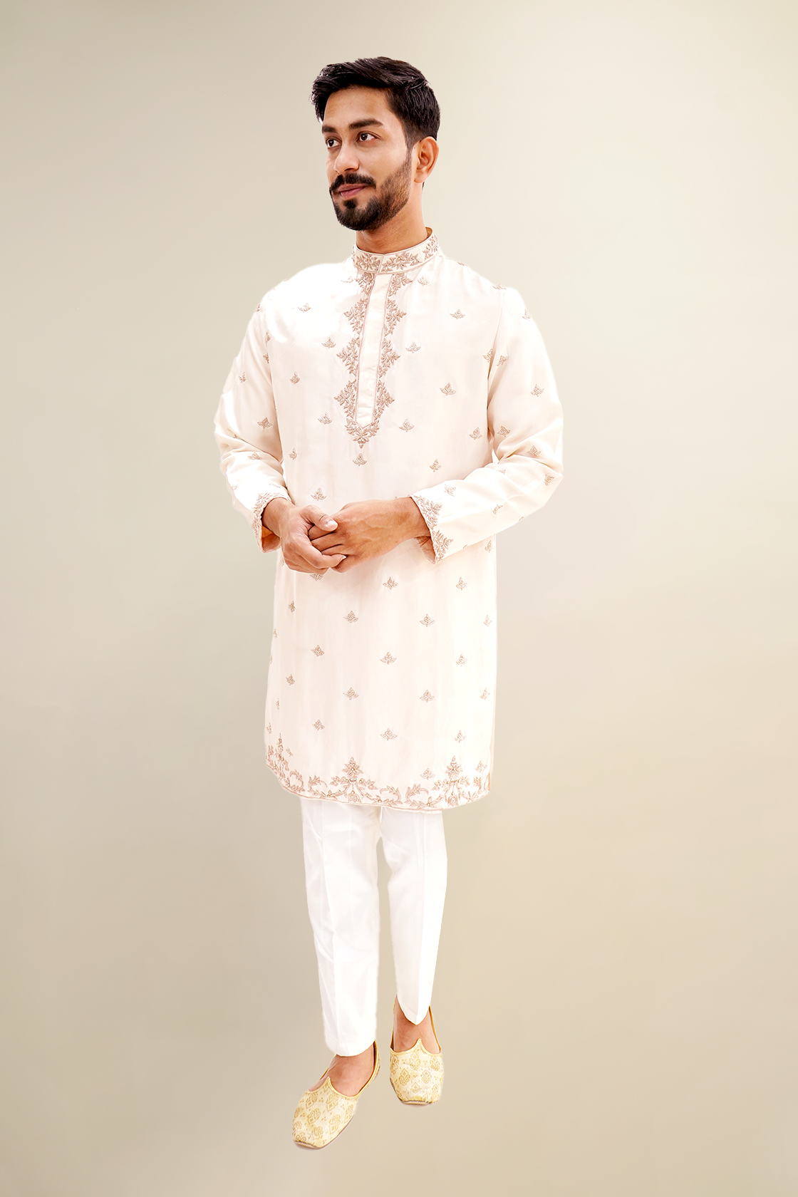 A man wearing a rose pink habutai kurta with zardozi butta work, standing with a smile.