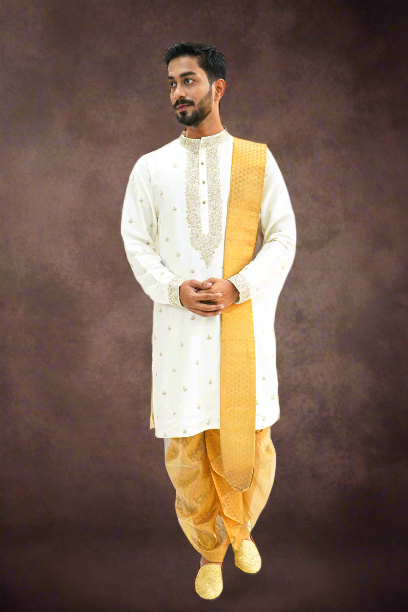A man wearing a light cream silk kurta with Zari embroidery, paired with a matching dhoti and stole.