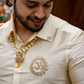 Man wearing a cream-colored traditional outfit with intricate designs and a necklace.