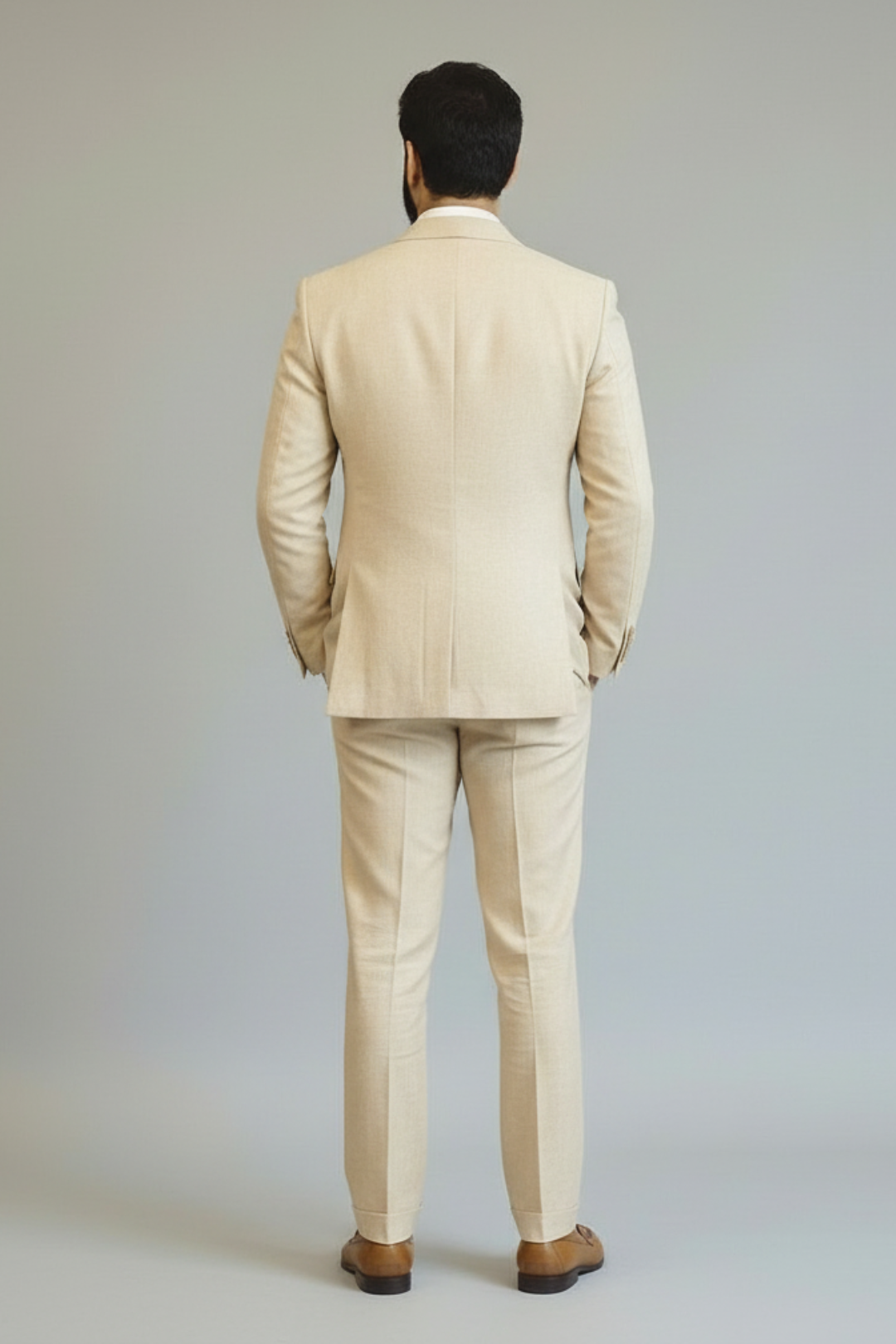 Man wearing a beige suit standing against a plain background