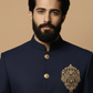 Man wearing a dark blue embroidered jacket with gold buttons on a beige background