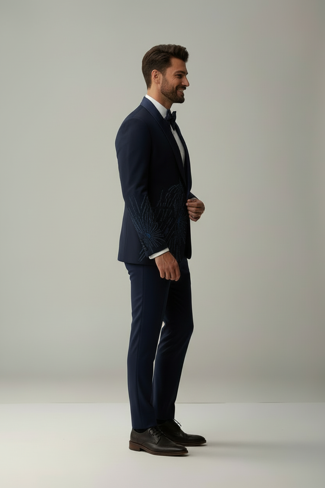 Man wearing a navy suit standing against a plain background