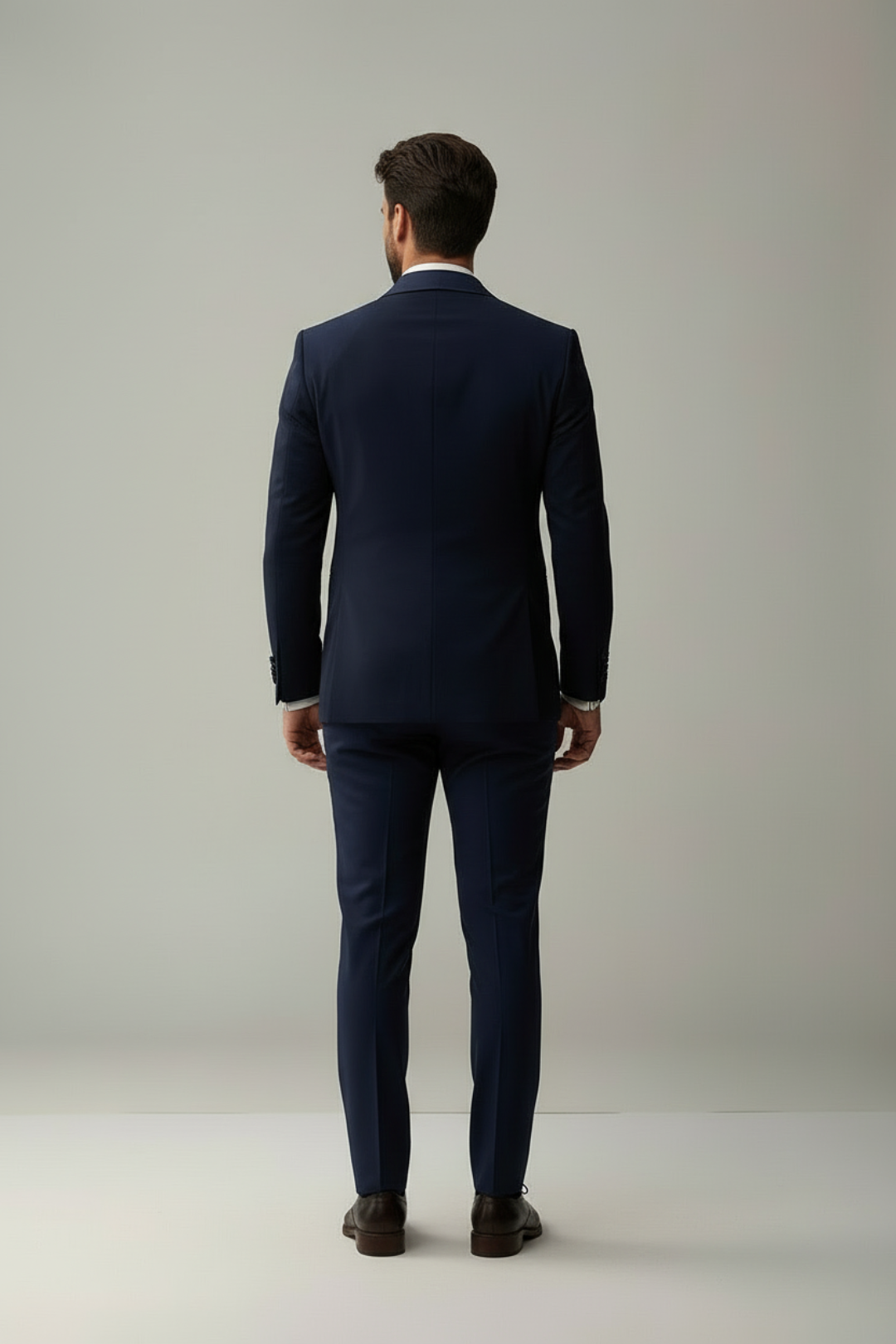 Man wearing a navy suit standing against a plain background