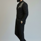 Man wearing a black suit with embroidery on a plain background
