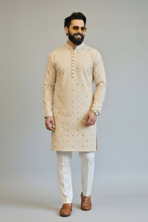 Man wearing a beige kurta with white pants on a plain background