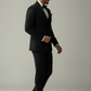 Man wearing a black suit and bow tie on a plain background