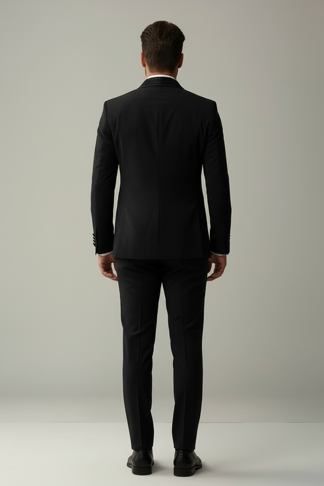 Man wearing a black suit against a plain background