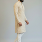 Man wearing a beige sherwani with white pants on a plain background