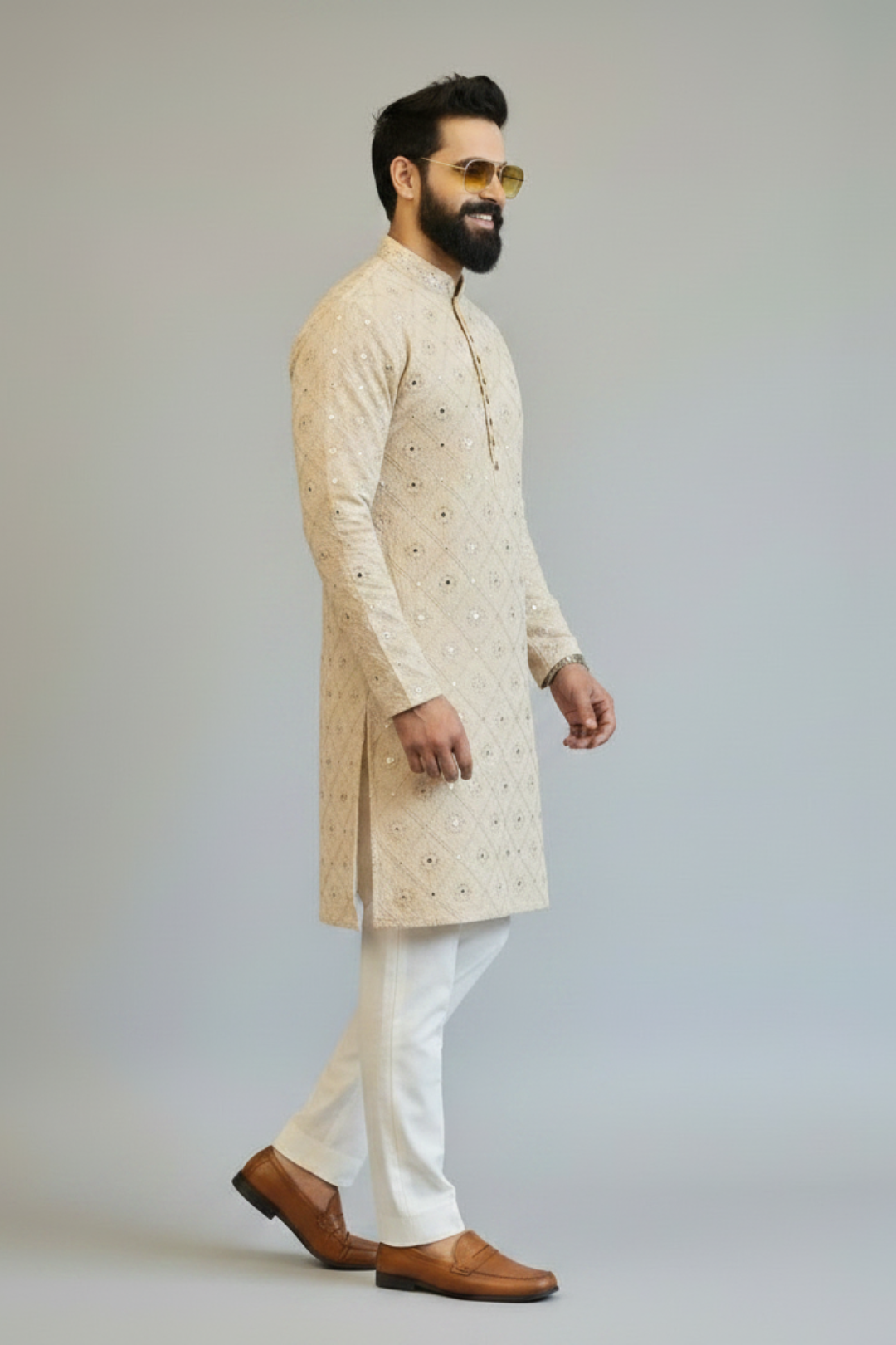 Man wearing a beige sherwani with white pants on a plain background