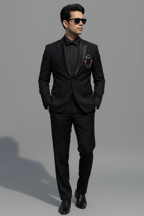 Man wearing a black tuxedo with a smiley face pocket square on a gray background