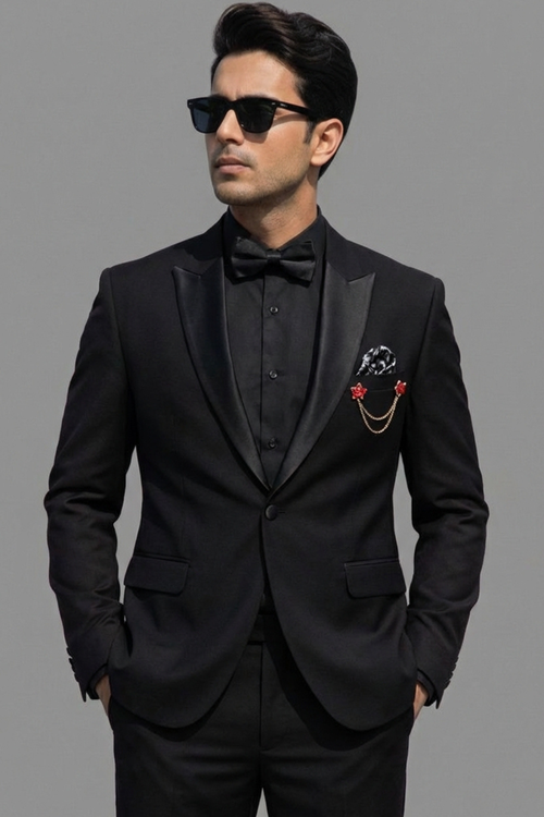 Man wearing a black tuxedo with a bow tie and pocket square on a gray background