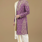 Man wearing a purple embroidered sherwani with a white stole against a beige background
