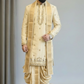 Man wearing a traditional beige sherwani with a turban against a plain background