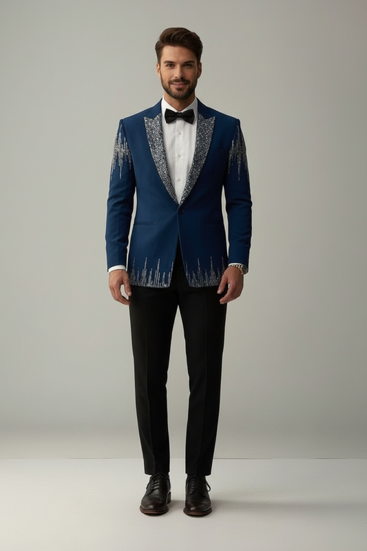 Man wearing a blue tuxedo with silver embroidery on a plain background