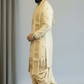 Man wearing a traditional cream sherwani with a turban against a plain background