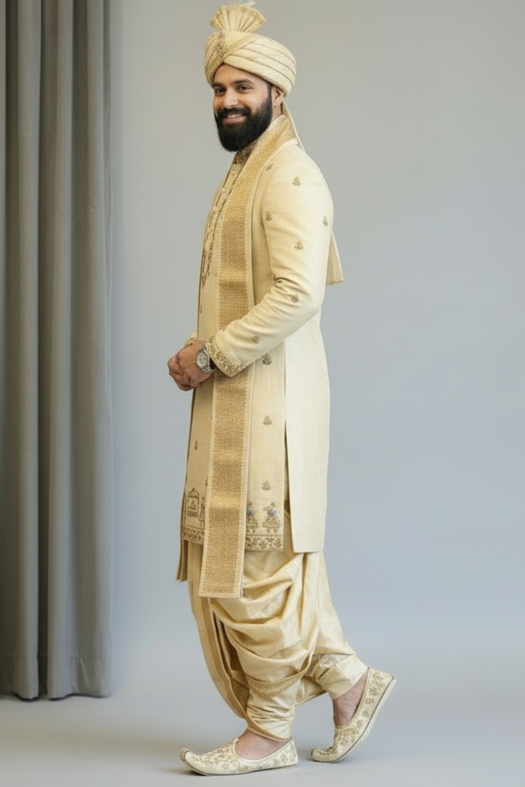 Man wearing a traditional cream sherwani with a turban against a plain background