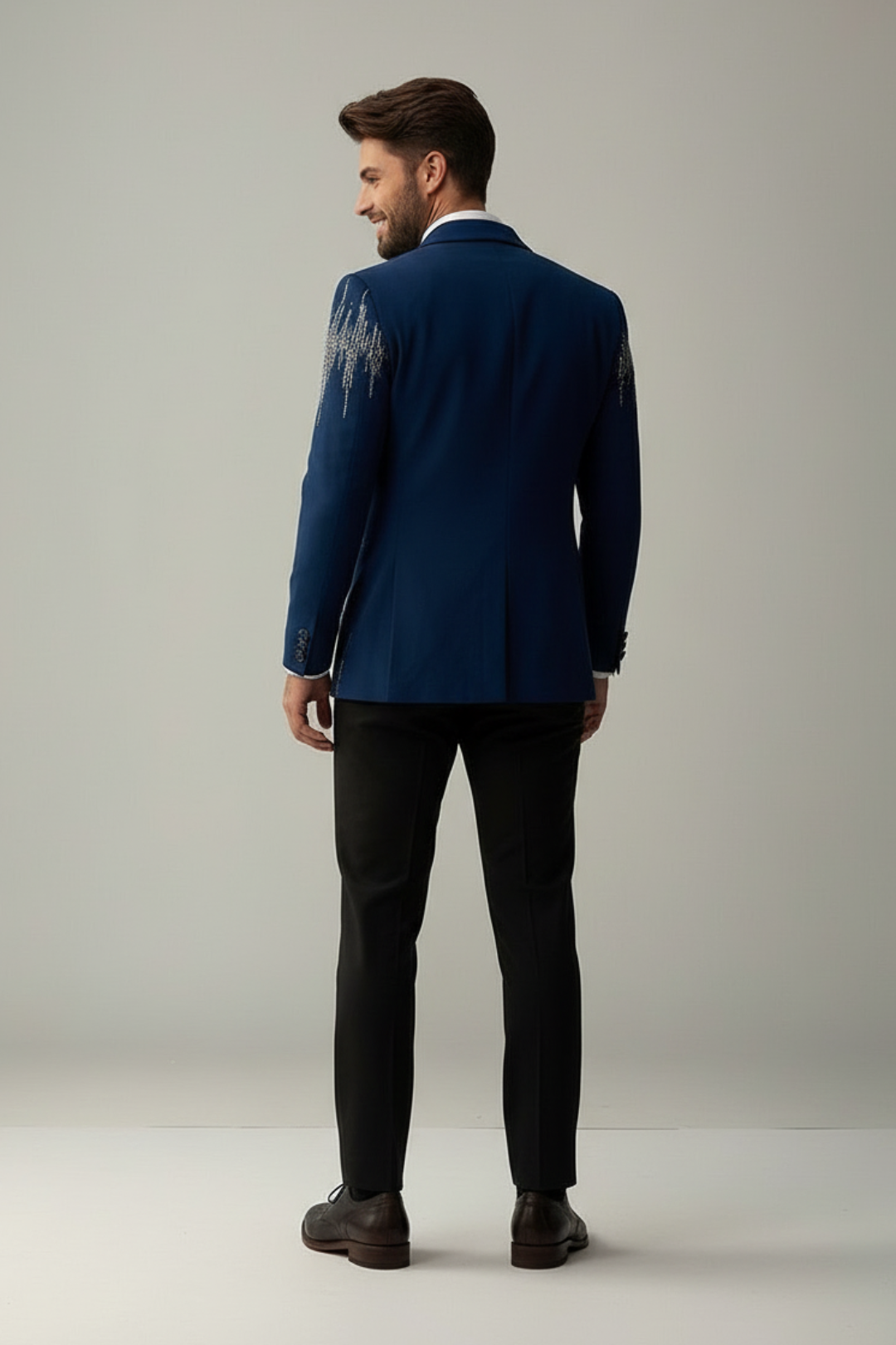 Man wearing a blue suit standing against a plain background