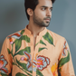 Man wearing a peach-colored shirt with floral patterns against a gray background