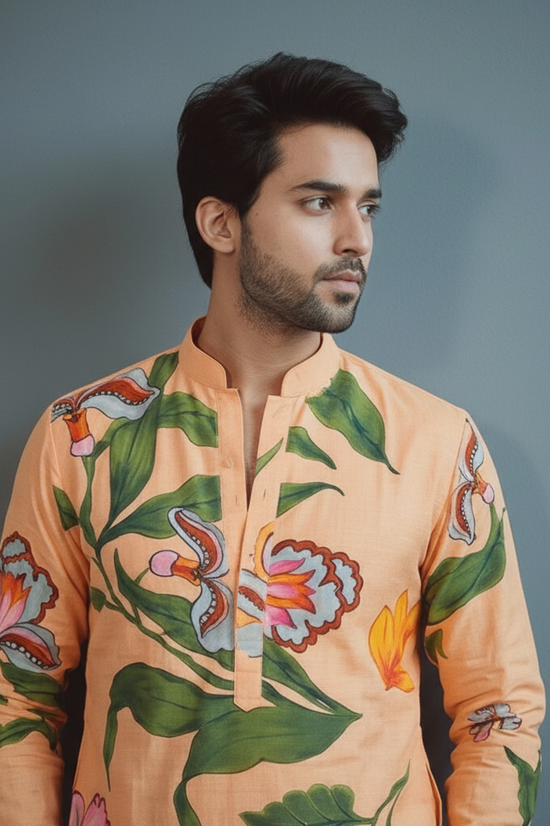 Man wearing a peach-colored shirt with floral patterns against a gray background