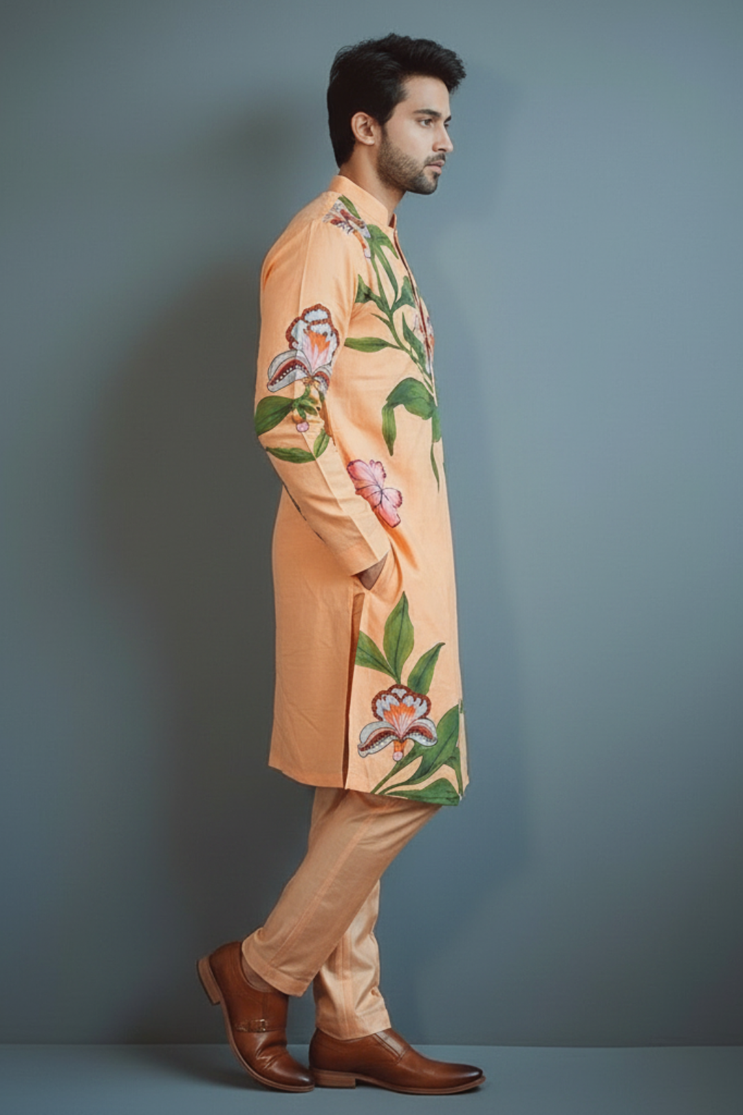 Man wearing a peach kurta with floral patterns against a gray background
