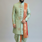 Man wearing a light green sherwani with a red and gold dupatta on a plain background
